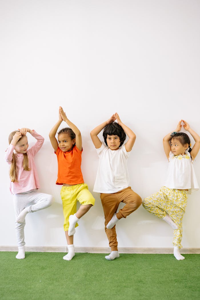 services-03 Four diverse children practicing yoga indoors, promoting fun and exercise in a learning environment.